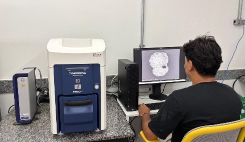 Imagens de microscopia eletrônica de varredura (MEV) exibidas em tela, com o doutorando Mateus Andrade Rodrigues.